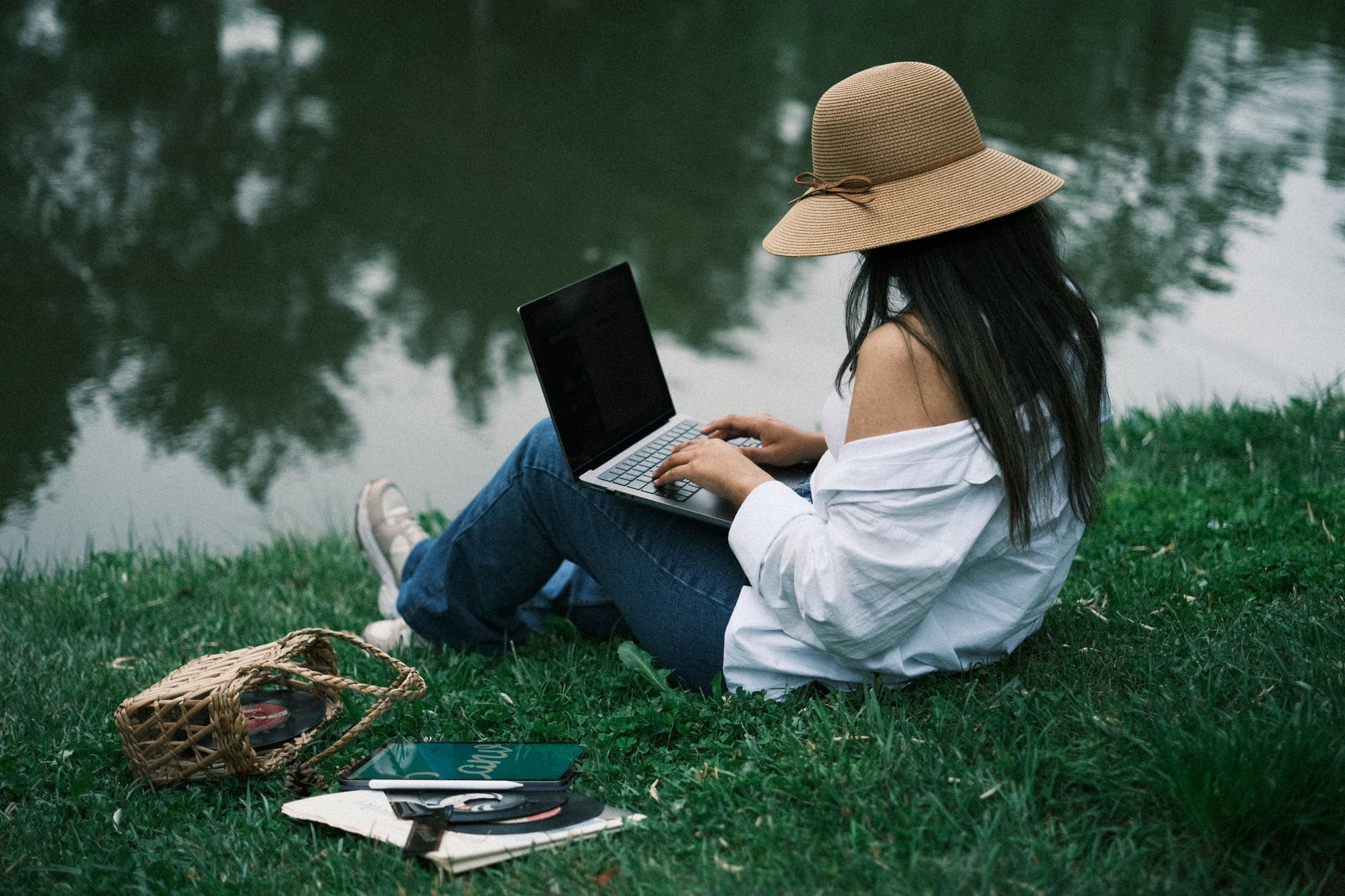 Une femme travaille sur son ordinateur portable au bord d'un lac paisible, au grand air.